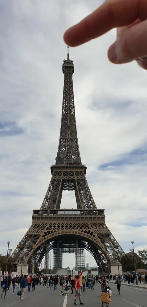 Illusion d'optique où le doigt touche la pointe de la Tour Eiffel